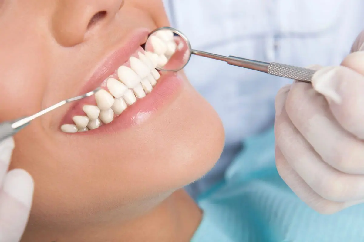 A woman is holding a tooth brush and teeth